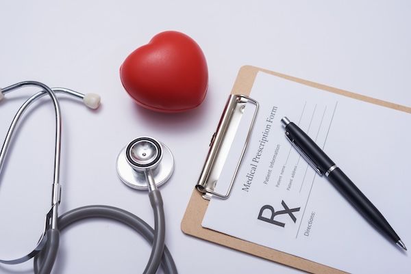 Stetoscopio con cuore. Stetoscopio e cuore rosso su tavolo di legno. Concetto di assicurazione sanitaria ospedaliera. Idea per la Giornata Mondiale della Salute del Cuore. Concetto di medicina o farmacia. Modulo medico vuoto pronto per essere utilizzato prima del pacemaker