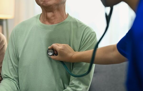 Medico che utilizza uno stetoscopio per ascoltare la respirazione o i battiti cardiaci di un paziente maschio maturo. Concetto di assistenza sanitaria per un paziente con pacemaker