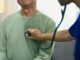 Medico che utilizza uno stetoscopio per ascoltare la respirazione o i battiti cardiaci di un paziente maschio maturo. Concetto di assistenza sanitaria per un paziente con pacemaker