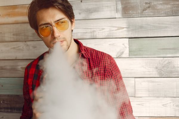 Uomo con stile ed elegante in una città con sigaretta elettronica il fumo è un fattore di rischio per la prevenzione cardiovascolare
