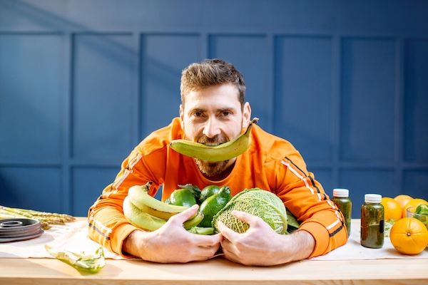 Vegetariano con verdure fresche su sfondo blu per dieta prevenzione cardiovascolare