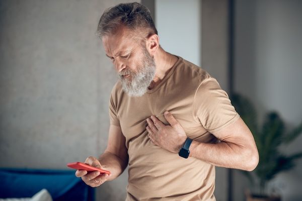 Infarto del miocardio. Un uomo barbuto di mezza età ha un attacco di cuore. concetto di prevenzione cardiovascolare