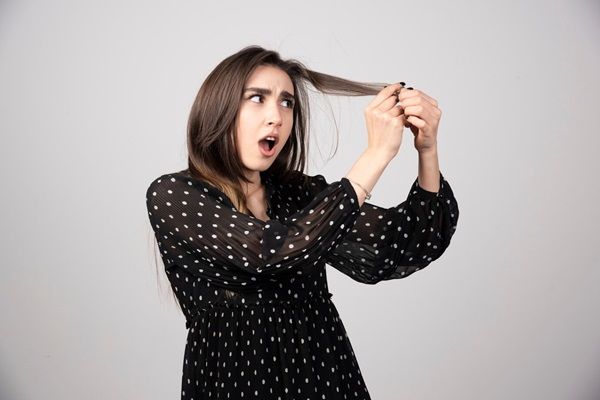 Una bella donna giovane che tiene in mano i suoi capelli sani e lucenti