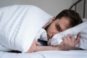 uomo ansioso sdraiato a letto su un fianco