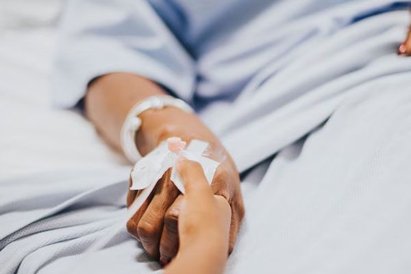 primo-piano-delle mani-nel-letto-d'ospedale