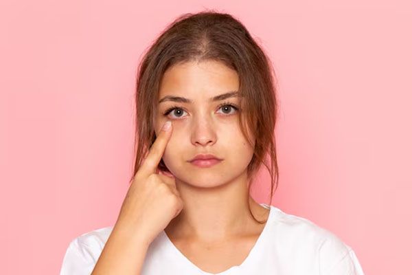 giovane donna in camicia bianca che mostra il suo occhio