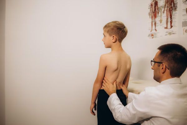 ortopedico che visita un bambino con mal di schiena