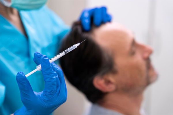 primo piano della mano del medico che tiene la siringa - costo trapianto capelli Turchia