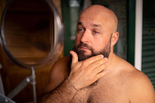 uomo calvo che si guarda pensieroso allo specchio - miglior trapianto capelli Italia 