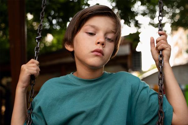 vista frontale di un bambino triste sull'altalena