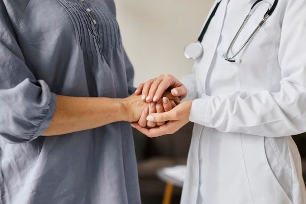 Primo piano delle mani del medico che tengono le mani del paziente anziano in un centro di recupero