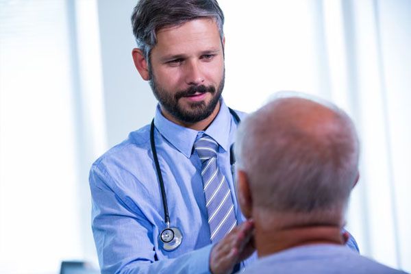 un giovane medico esamina un paziente anziano calvo - miglior trapianto capelli Italia