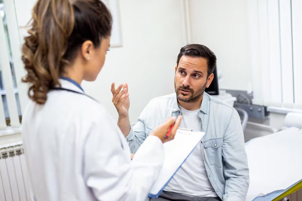 Un giovane preoccupato parla con un medico che tiene in mano una cartella