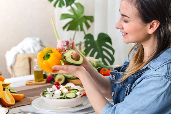 giovane donna felice che mangia insalata al tavolo