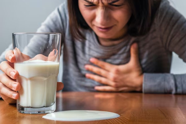 Donna con disagio mentre tiene un bicchiere di latte sul tavolo