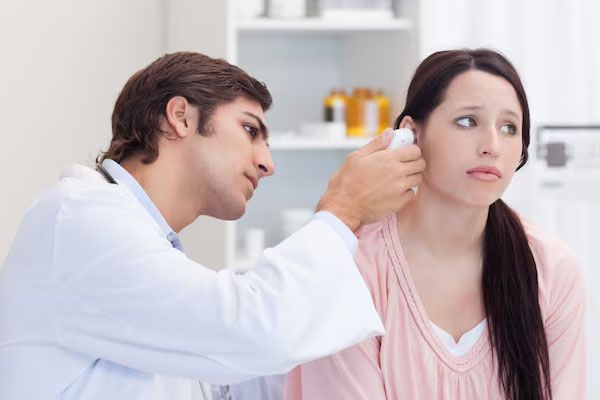 Medico che esamina l'orecchio di un giovane con un'espressione preoccupata