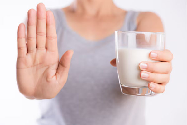 Primo piano di una donna che fa il segnale di stop con una mano mentre tiene un bicchiere di latte nell'altr