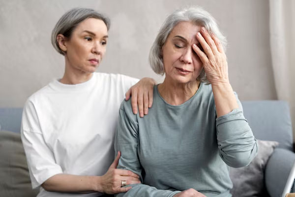 Una giovane donna accarezza la spalla di una donna anziana con il viso preoccupato