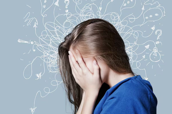 Vista di profilo di una donna che si copre il viso con le mani davanti a un muro decorato con scarabocchi