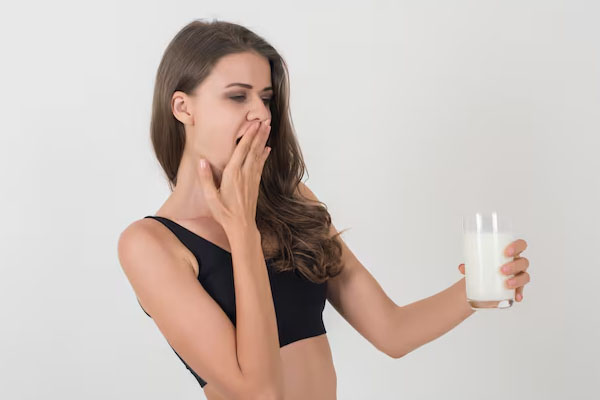 bella donna che guarda con espressione sorpresa un bicchiere di latte