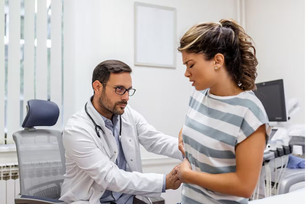 Medico che tocca il fianco di una donna con un'espressione di dolore