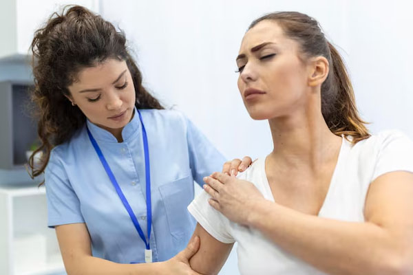 Il medico esamina la spalla di una giovane donna