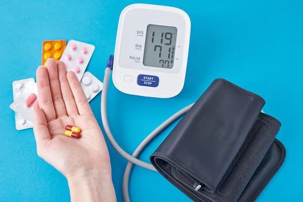 Mano che tiene capsule su blister di pillole e un misuratore di pressione sanguigna