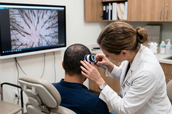 Dermatologo che esamina la densità dei capelli nella regione posteriore del cuoio capelluto durante una valutazione specialistica