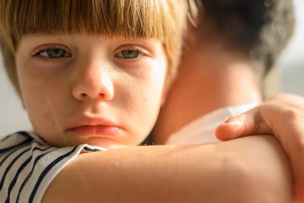 Bambino che si morde le mani rappresentando i comportamenti autolesivi tipici della sindrome
