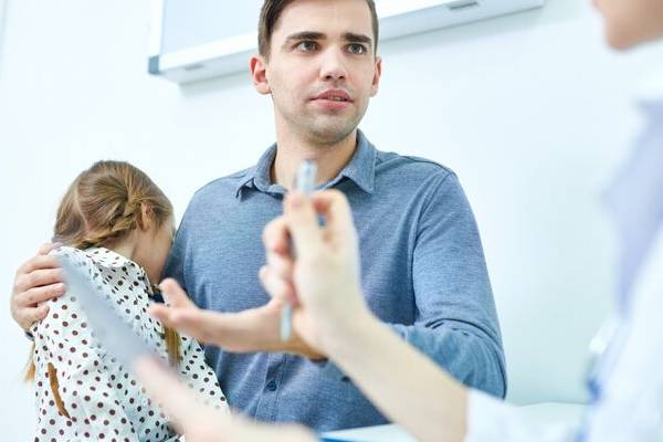 Medico che spiega i sintomi e le cause ai genitori